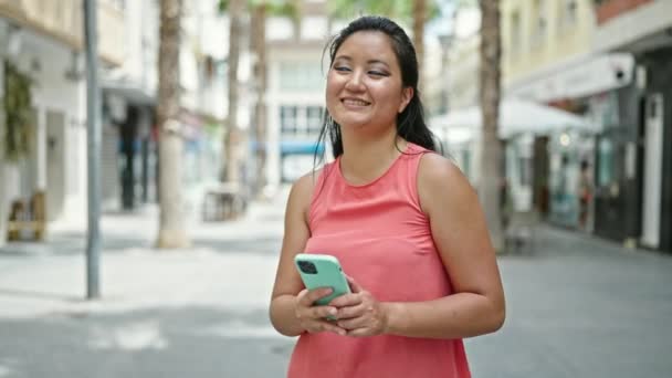 Joven mujer china bailando escuchando música en un smartphone en la calle - Metraje, vídeo