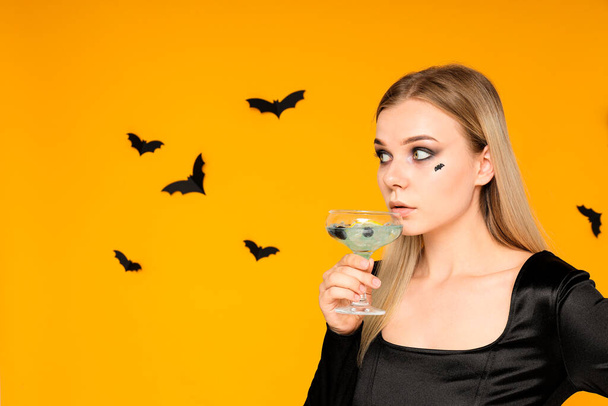 Uma menina em uma festa no estilo de Halloween com um coquetel em suas mãos - Foto, Imagem
