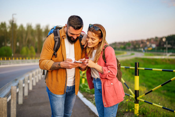 Glücklich lächelndes Paar nutzt Karten auf dem Smartphone in der Stadt. Touristen besichtigen die Stadt. - Foto, Bild