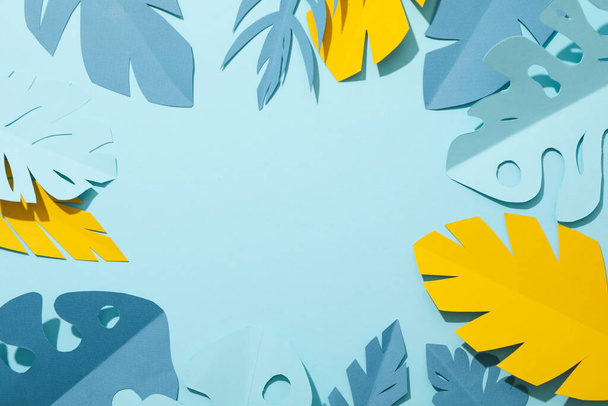 Keltaiset ja siniset trooppiset lehdet pastelliväreissä sinisellä pohjalla - Valokuva, kuva