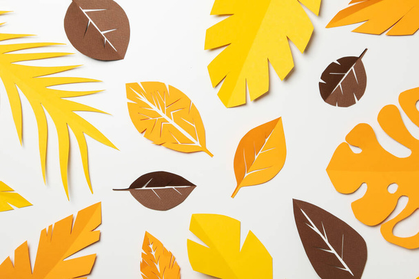 Бумага желтые и коричневые тропические листья на светлом фоне - Фото, изображение