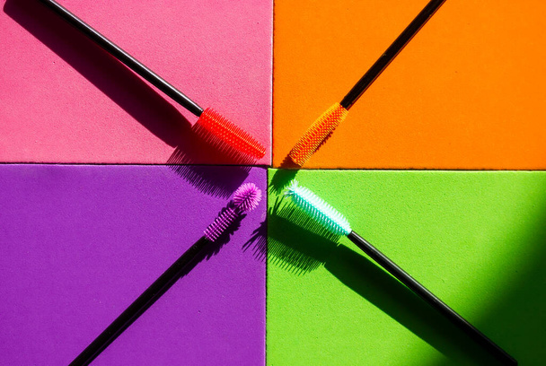 Set of multicolored silicone mascara brushes on a multicolored bright background. Green, pink, purple, orange lash brushes. Modern decorative cosmetics for women. Female beauty and glamour fashion.  - Photo, Image