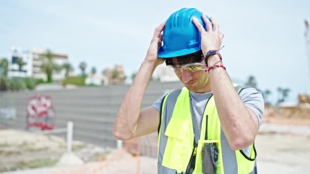 Молодий іспаномовний чоловік архітектор посміхається впевнено носити хардхат на будівельному майданчику - Кадри, відео