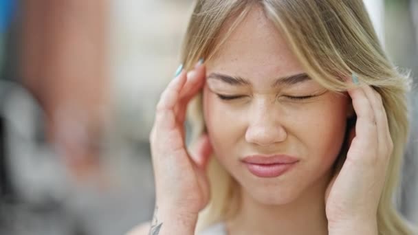 Νεαρή ξανθιά γυναίκα που υποφέρει από πονοκέφαλο στο δρόμο - Πλάνα, βίντεο