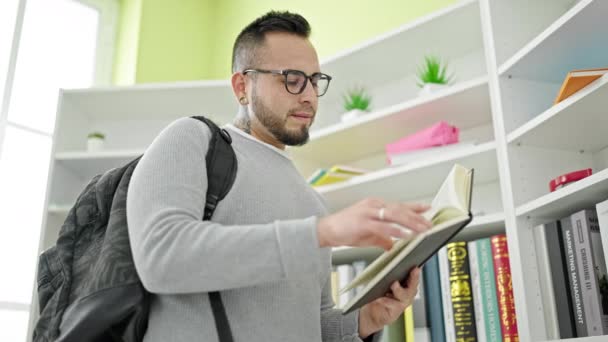 Hombre hispano de pie leyendo libro en la universidad de la biblioteca - Metraje, vídeo
