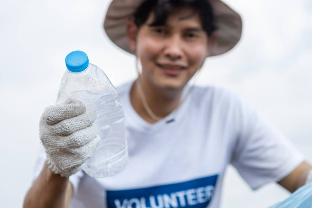 Close up lixo garrafa de plástico na mão voluntários do sexo masculino, conduzindo a cooperação ambiental, economizando mundo reduzindo o aquecimento global, lixo saco de plástico limpo em atrações naturais. - Foto, Imagem