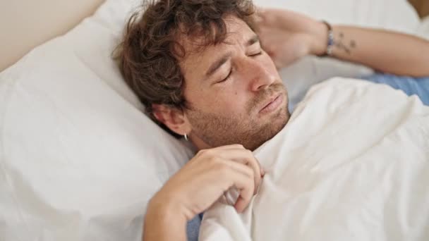 Fiatal spanyol férfi fekszik az ágyon stresszes a hálószobában - Felvétel, videó