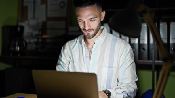 Giovane ispanico uomo d'affari lavoratore utilizzando laptop sorridente in ufficio - Filmati, video