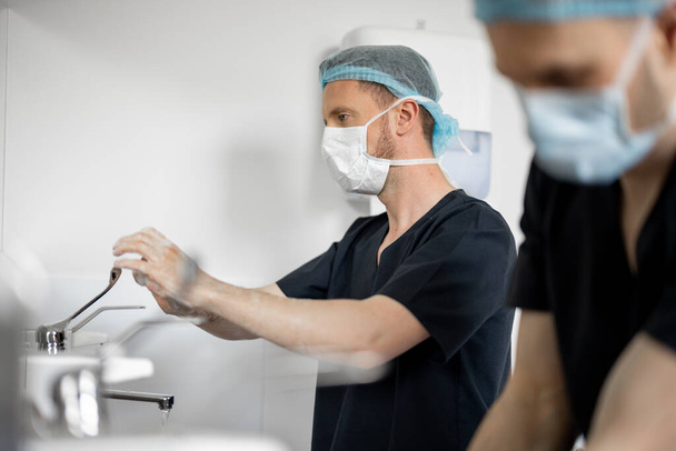 Két sebész gondosan megmosta a kezét, hogy felkészüljön egy műtétre. A sterilitás és a műtét fogalma - Fotó, kép