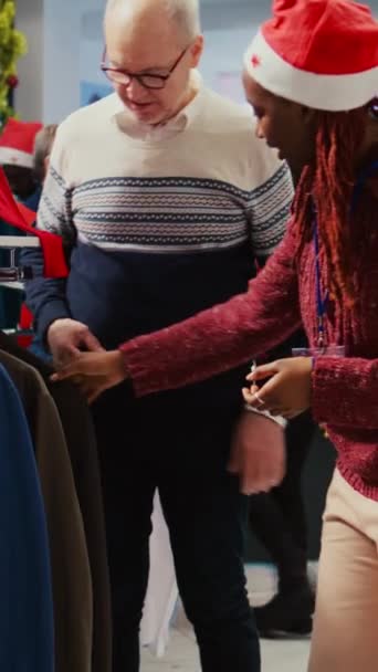 Függőleges videó Afrikai-amerikai bolt menedzser upselling stílusos blézer gazdag idős ügyfél, meggyőzve őt a ruhadarab mesterien kialakított minőségi anyagok ünnepi díszes ruházat - Felvétel, videó