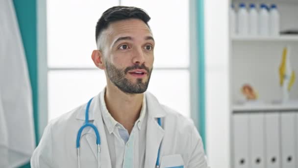 Joven médico hispano con consulta médica midiendo temperatura con termómetro en la clínica - Metraje, vídeo