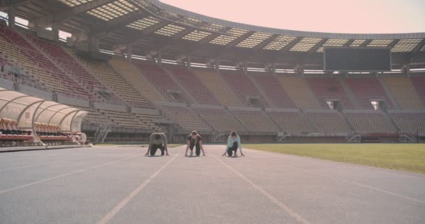 Három fiatal versenyez a futópályán egy stadionban. - Felvétel, videó