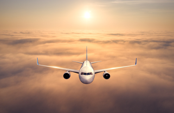 Airplane is flying above the clouds at sunset. Landscape with passenger airplane, beautiful clouds, golden sky. Aircraft is taking off. Business travel. Commercial plane. Aerial view of plane - Photo, Image