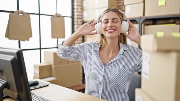 Mujer rubia joven comercio electrónico trabajador de negocios escuchando música bailando en la oficina - Imágenes, Vídeo