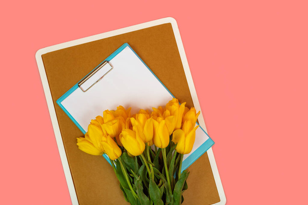 Bouquet of yellow tulips on bulletin cork board and white paper. Space for texts. Copy space, mock up - Photo, Image