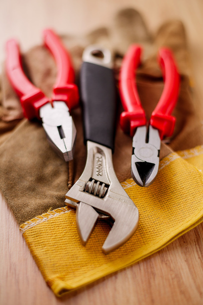 Adjustable wrench, pliers and wire cutters on top of the protective gloves - Photo, Image