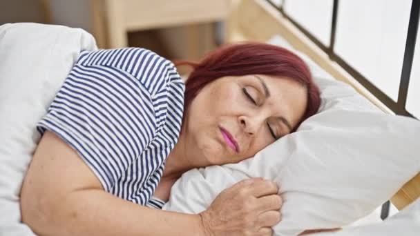 Orta yaşlı bir kadın yatak odasında gürültü için kulaklarını kapatıyor. - Video, Çekim
