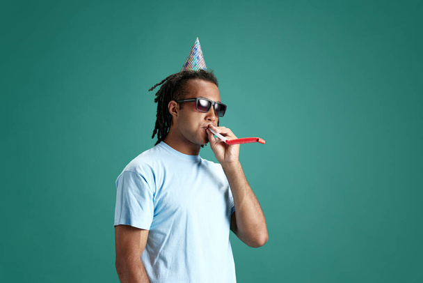 Young man wearing hair accessories, celebrating birthday against green studio background. Party and fun. Concept of youth, human emotions, lifestyle, fashion, facial expressions, ad - Foto, Bild