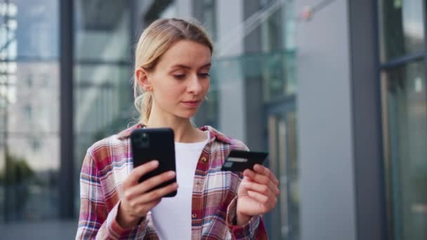Melko nuori positiivinen nainen käyttää matkapuhelin tilalla luottokortti - Materiaali, video