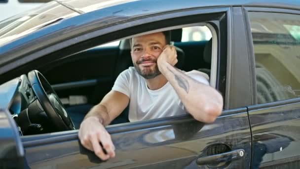 Joven hispano sosteniendo la llave de un auto nuevo haciendo un gesto de pulgar hacia arriba sonriendo en la calle - Imágenes, Vídeo