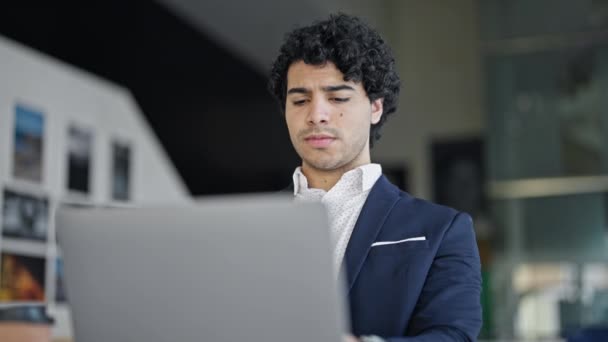 Jovem latino homem trabalhador de negócios usando laptop olhando chateado no escritório - Filmagem, Vídeo