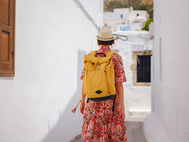 Ładna azjatycka kobieta w boho sukience Ciesząca się słonecznym dniem na greckich wyspach. Podróż do Lindos, śródziemnomorskich wysp sezon turystyczny. Turystka na wakacjach w Grecji spacerująca ulicami Lindos. - Zdjęcie, obraz