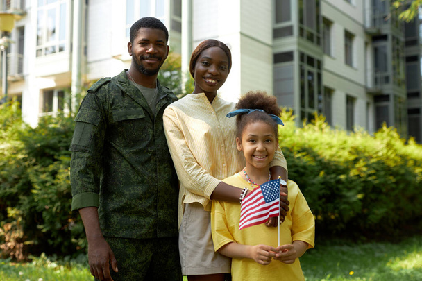 Egy boldog afro-amerikai család portréja katonai apával, akik mosolyognak a kamera előtt a függetlenség napján. - Fotó, kép
