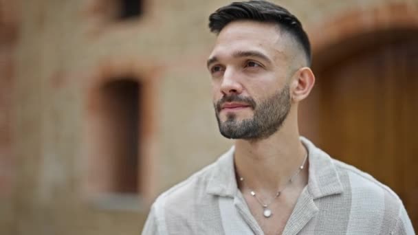 Fiatal spanyol férfi áll komoly arckifejezéssel az utcán - Felvétel, videó