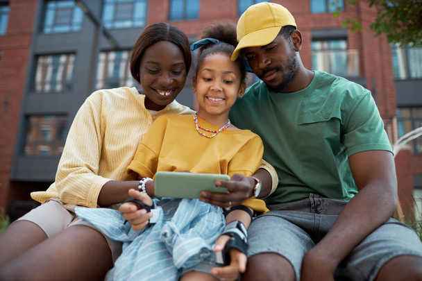 Afro-Amerikaanse familie zitten op bank met kind en met behulp van digitale tablet - Foto, afbeelding