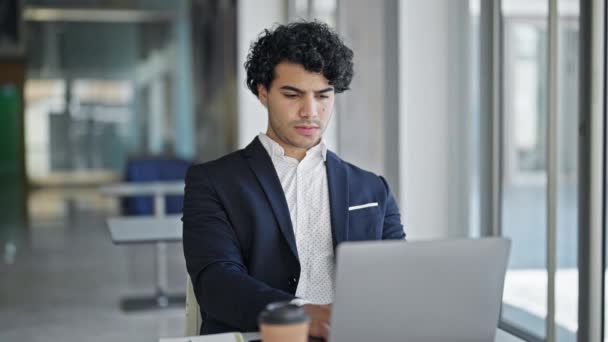 Молодий латинський працівник бізнесу використовує ноутбук з жестом переможця в офісі - Кадри, відео