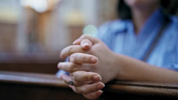 Joven mujer hispana hermosa rezando en un banco de la iglesia  - Imágenes, Vídeo