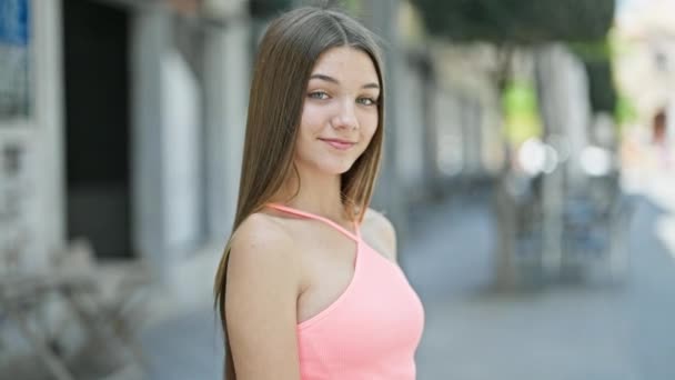 Νεαρό όμορφο κορίτσι χαμογελά αυτοπεποίθηση στέκεται στο δρόμο - Πλάνα, βίντεο