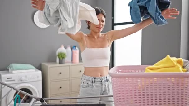 Jovem bela mulher hispânica estressada jogando roupas na lavanderia - Filmagem, Vídeo