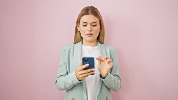 Молодая блондинка бизнес-работница улыбаясь уверенно сделать селфи на смартфоне на изолированном розовом фоне - Кадры, видео