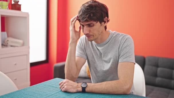Fiatal spanyol férfi hangsúlyozta ül az asztalon ebédlőben - Felvétel, videó
