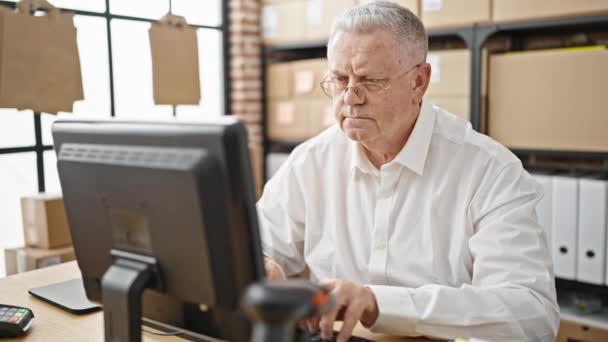 Седовласый мужчина среднего возраста, торгующий в электронной коммерции, с помощью компьютера, улыбающийся в офисе - Кадры, видео