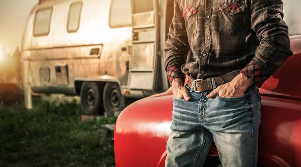 アメリカ西部のカウボーイは,彼のパンツポケットに手を入れ,彼のトラックとトラベルトレーラーの隣に滞在 - 写真・画像