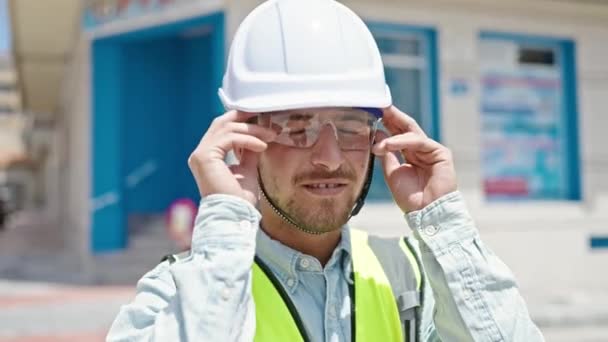 Fiatal kaukázusi férfi építész mosolygós magabiztos kiviszi szemüveg az építkezés helyén - Felvétel, videó