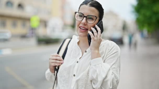 Nuori kaunis latino nainen puhuu puhelimessa kadulla - Materiaali, video
