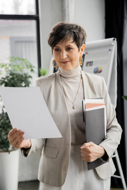 exitosa mujer madura empresaria con carpeta mirando documento en la oficina, planificación de negocios - Foto, Imagen