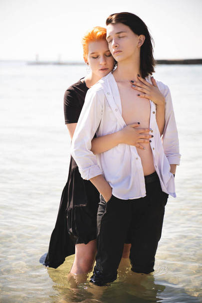 dos amantes chico y chica son felices caminando y abrazándose en la playa de arena cerca del mar - Foto, Imagen