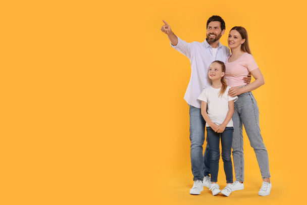 Happy family on orange background, space for text - Valokuva, kuva