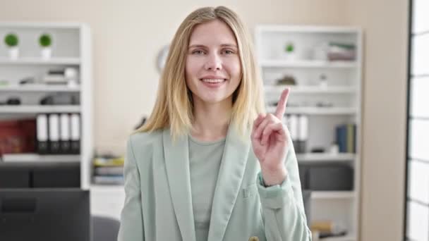 Junge blonde Geschäftsfrau lächelt selbstbewusst und macht Geste im Büro - Filmmaterial, Video
