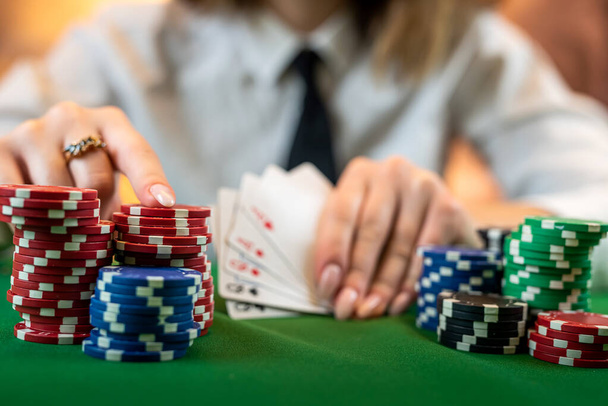 ポーカーを完璧にプレイする方法を知っている女性は、カードやチップとポーカーテーブルに座っています。マネーゲームのコンセプト。背景に隔離され - 写真・画像