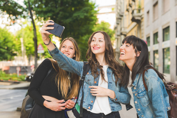 Τρεις νεαρές γυναίκες χιλιετίες βγάζουν selfie με smartphone - Φωτογραφία, εικόνα