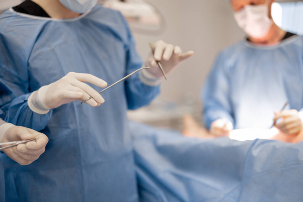 Chirurg trzyma narzędzia chirurgiczne podczas operacji, zbliżenie - Zdjęcie, obraz