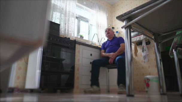 Suorapuheinen Pensive vanhempi istuu kotona yksin keittiön ikkunan, rento kohtaus huomaavainen vanhempi henkilö yksinäisyydessä yksin keskiluokan asuinpaikka - Valokuva, kuva