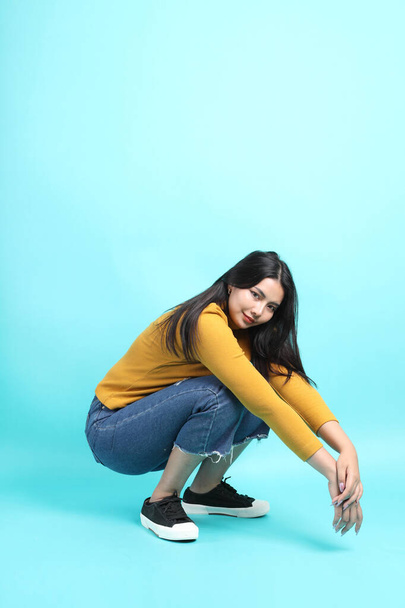 The Asian woman in casual clothes sitting on the green background. - Photo, Image