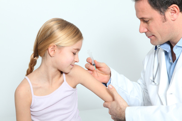 Doctor doing vaccine injection to blond little girl - Foto, Imagen