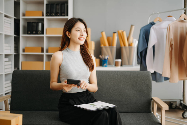 Young business owner woman prepare parcel box and standing check online orders for deliver to customer on tablet, laptop Shopping Online concept - 写真・画像